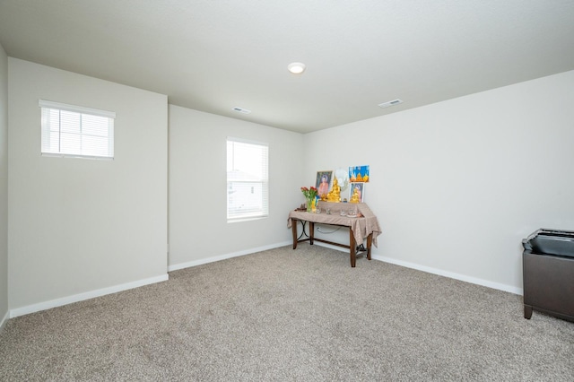 interior space with a wealth of natural light, visible vents, baseboards, and carpet flooring