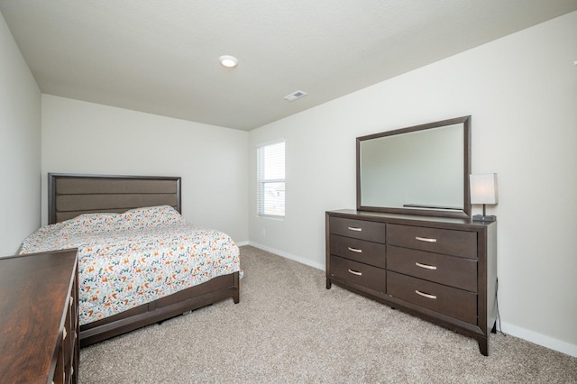 bedroom featuring baseboards, visible vents, and light carpet