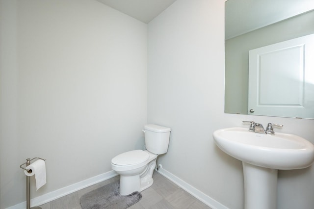 half bath featuring a sink, baseboards, and toilet