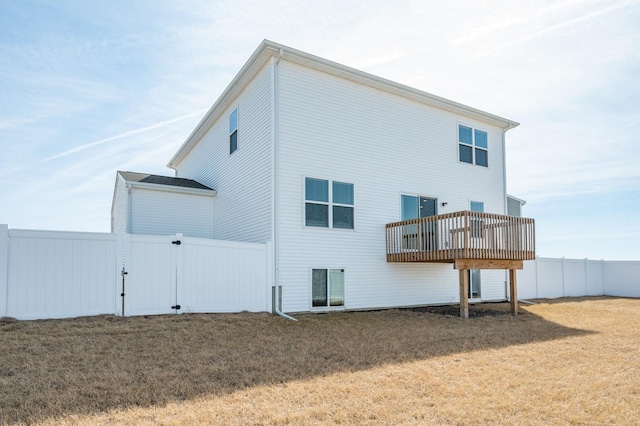 back of property with a lawn and fence