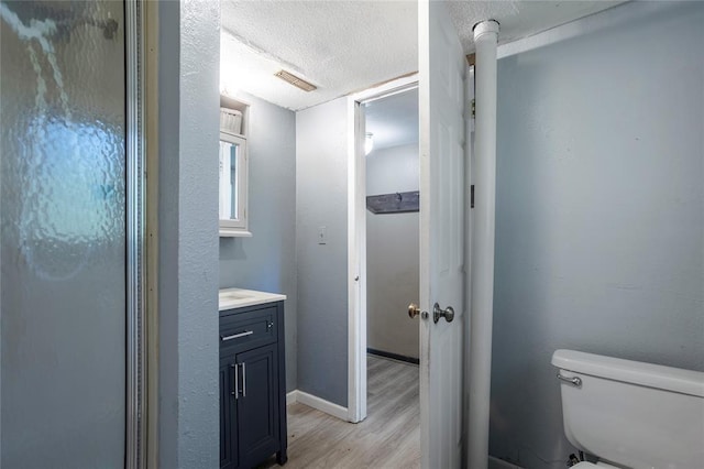 bathroom featuring visible vents, toilet, vanity, wood finished floors, and a textured ceiling