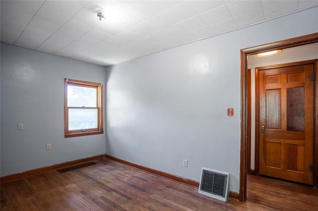 empty room featuring visible vents, baseboards, and wood finished floors