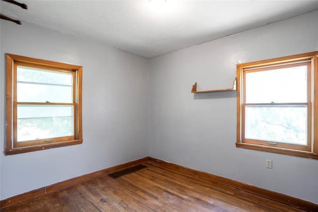 spare room with visible vents, baseboards, and wood-type flooring