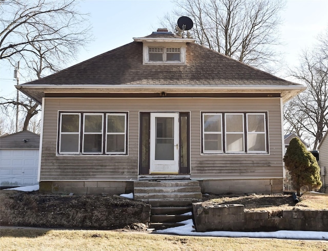 bungalow featuring entry steps, an outdoor structure, roof with shingles, and a chimney