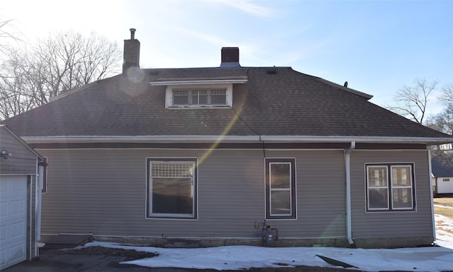 view of side of property featuring a garage and roof with shingles