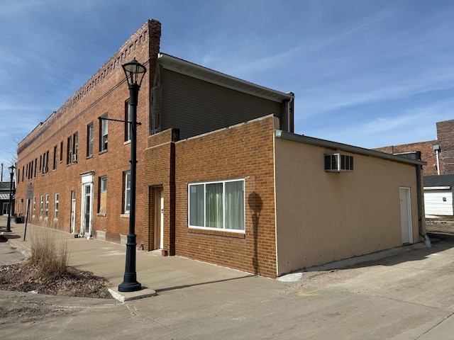 view of side of property featuring brick siding and a wall unit AC