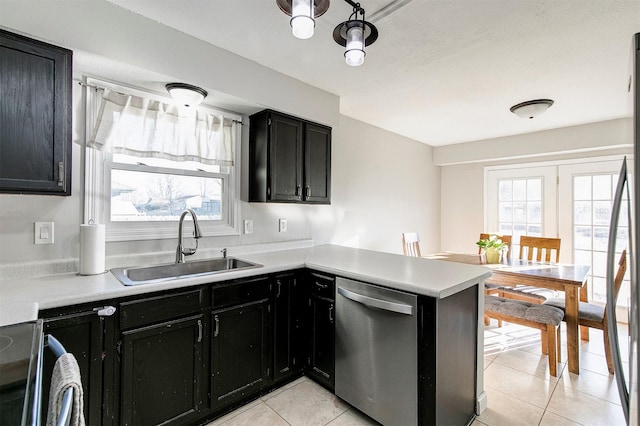 kitchen with a wealth of natural light, a sink, dark cabinetry, and stainless steel dishwasher