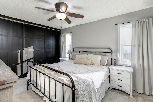 bedroom featuring light carpet, a textured ceiling, and a ceiling fan