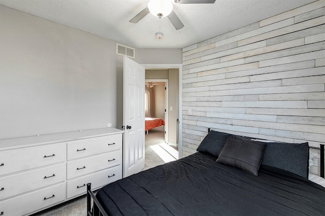 unfurnished bedroom with wooden walls, light colored carpet, visible vents, and a textured ceiling