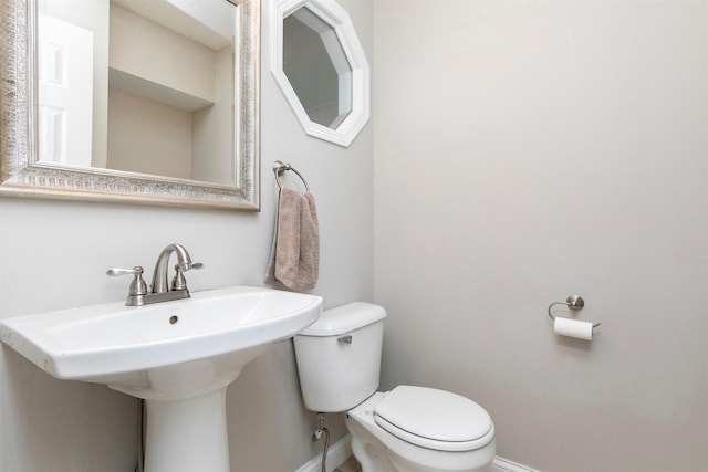 bathroom with toilet, baseboards, and a sink