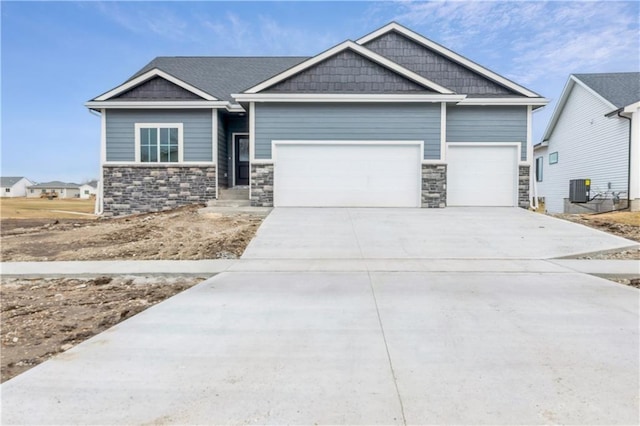 craftsman inspired home featuring stone siding, a garage, cooling unit, and concrete driveway