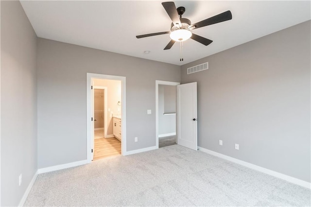 unfurnished bedroom with visible vents, ensuite bathroom, baseboards, light colored carpet, and ceiling fan