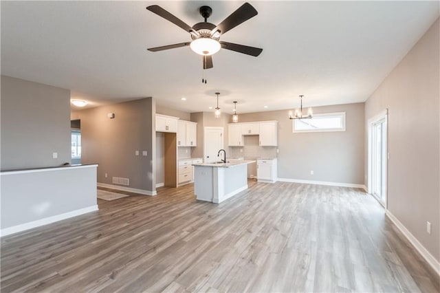 kitchen featuring a center island with sink, visible vents, light wood-style flooring, white cabinetry, and open floor plan