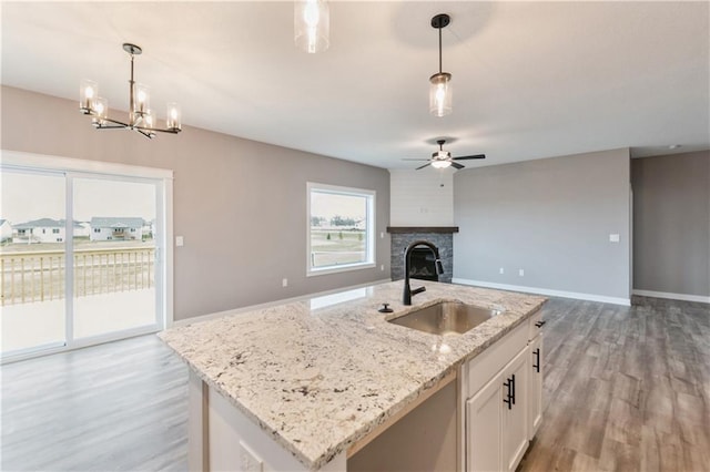 kitchen featuring a sink, pendant lighting, a fireplace, and white cabinetry