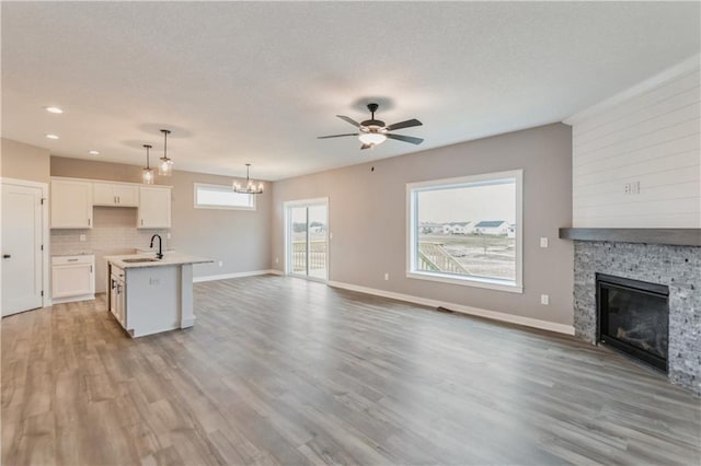 unfurnished living room featuring a sink, a stone fireplace, and light wood finished floors