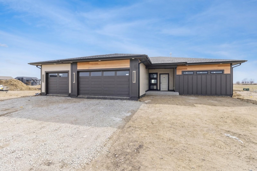 prairie-style home featuring an attached garage, driveway, and a shingled roof