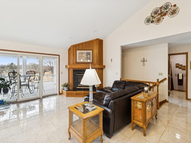 living area with light tile patterned floors, baseboards, high vaulted ceiling, and a tile fireplace