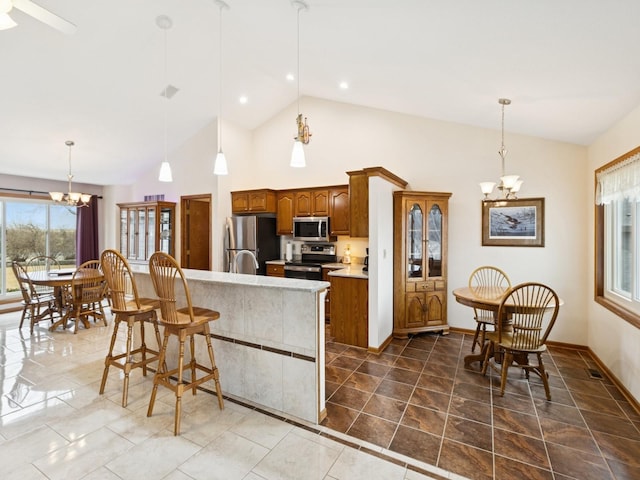 kitchen featuring an island with sink, a notable chandelier, stainless steel appliances, and light countertops