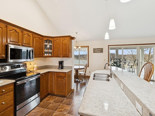 kitchen with dark tile patterned floors, a sink, stainless steel appliances, brown cabinetry, and glass insert cabinets