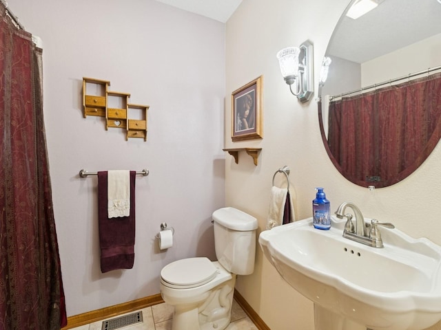 bathroom featuring baseboards, visible vents, a sink, tile patterned floors, and toilet