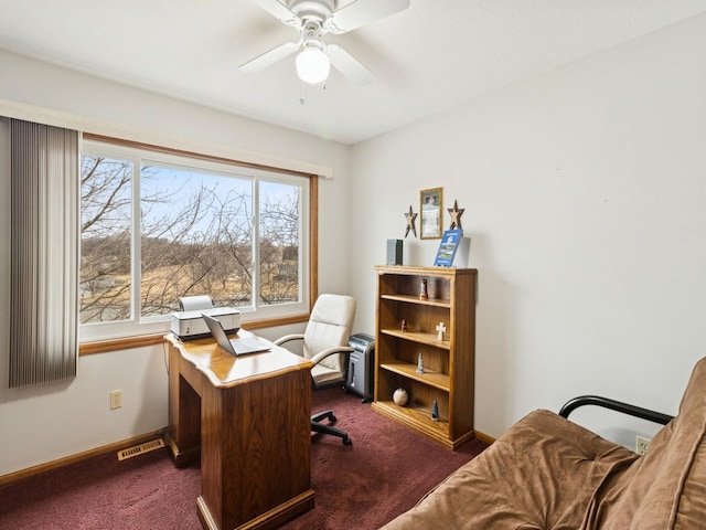 office space with dark colored carpet, visible vents, baseboards, and a ceiling fan