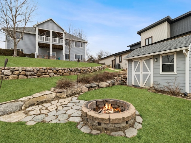 view of yard featuring an outdoor structure, a balcony, and an outdoor fire pit