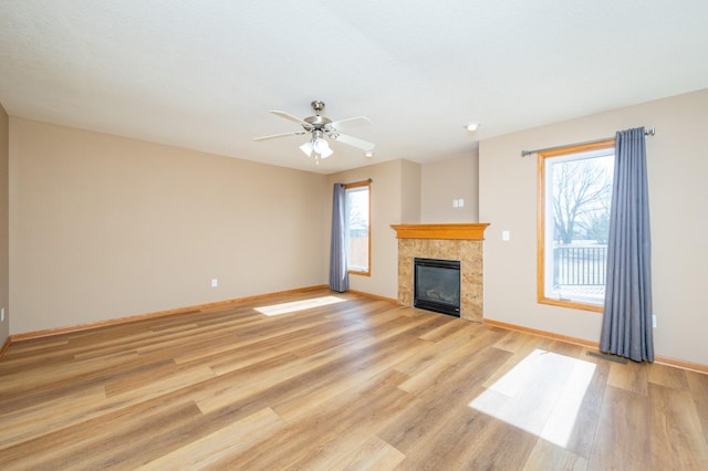 unfurnished living room with light wood-style floors, baseboards, and a tile fireplace