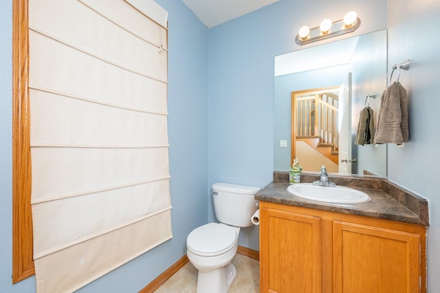 half bathroom featuring tile patterned floors, toilet, vanity, and baseboards