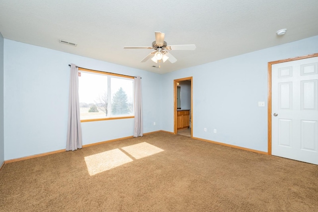 empty room featuring visible vents, baseboards, light colored carpet, a textured ceiling, and a ceiling fan