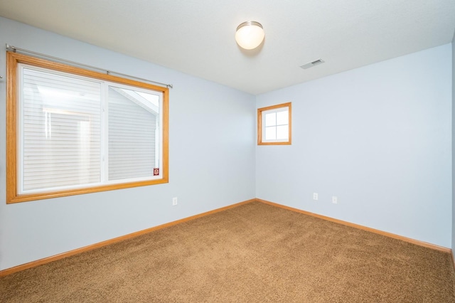 carpeted spare room featuring visible vents and baseboards