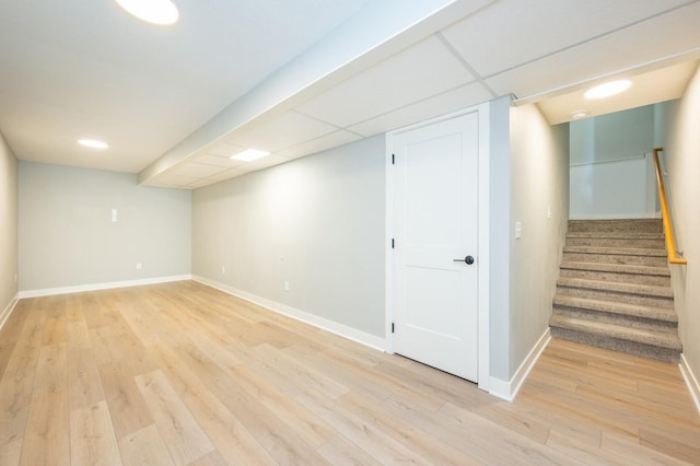 finished below grade area featuring stairway, light wood-style floors, and baseboards