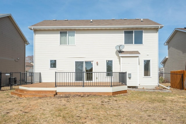 rear view of house with a yard, a deck, and fence