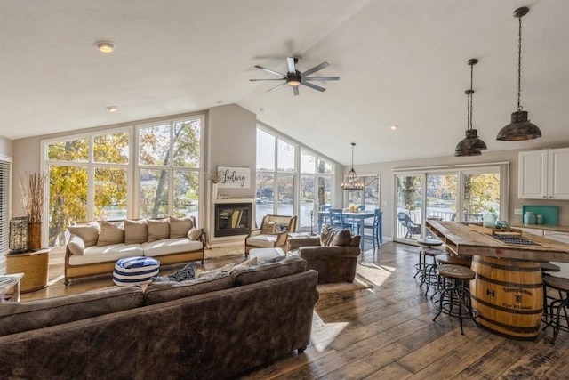 living room featuring a glass covered fireplace, high vaulted ceiling, dark wood-type flooring, and ceiling fan