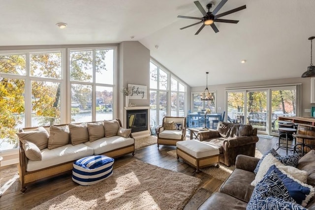 living area featuring a wealth of natural light, a glass covered fireplace, high vaulted ceiling, and hardwood / wood-style floors