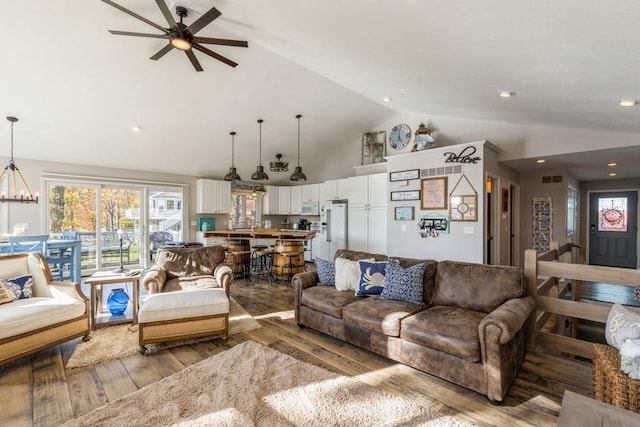 living room featuring high vaulted ceiling, wood finished floors, visible vents, and a chandelier