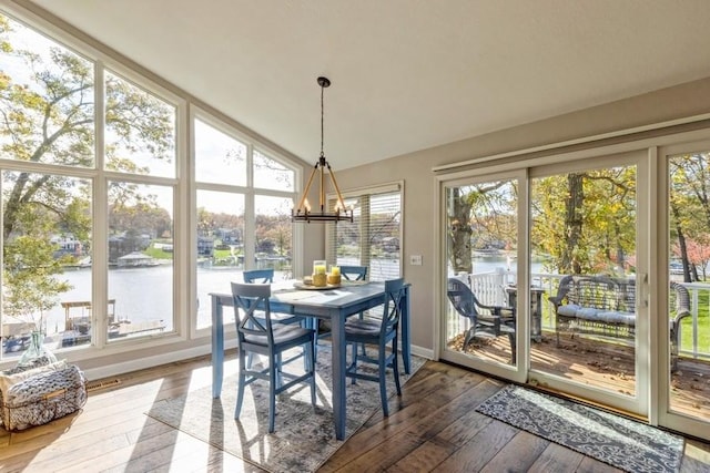 sunroom with a chandelier, vaulted ceiling, and a water view