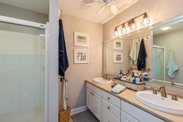 bathroom featuring double vanity, a shower stall, ceiling fan, and a sink