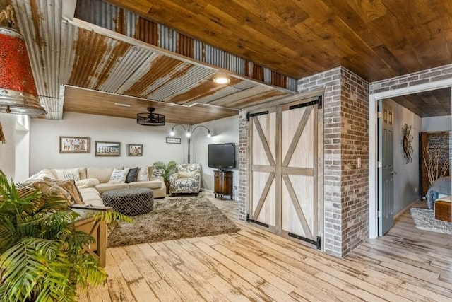 living room with brick wall, wood ceiling, a barn door, and wood-type flooring