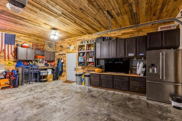 garage with wooden ceiling, stainless steel refrigerator with ice dispenser, and wood walls