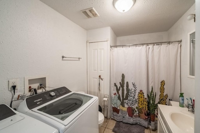 washroom featuring visible vents, washer and clothes dryer, a textured ceiling, light tile patterned floors, and laundry area