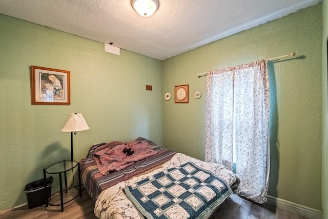 bedroom with wood finished floors, a textured wall, and a textured ceiling