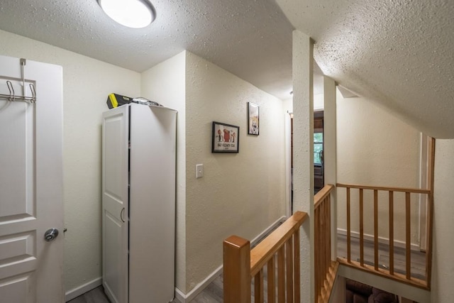 corridor featuring baseboards and a textured wall