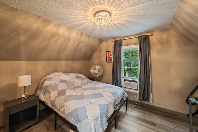 bedroom featuring cooling unit, a textured ceiling, lofted ceiling, and wood finished floors