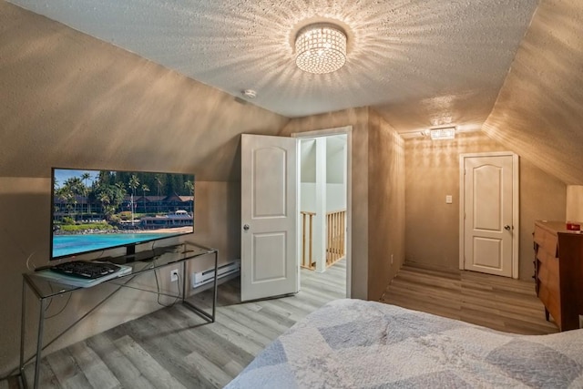 bedroom featuring a baseboard heating unit, vaulted ceiling, wood finished floors, and a textured ceiling