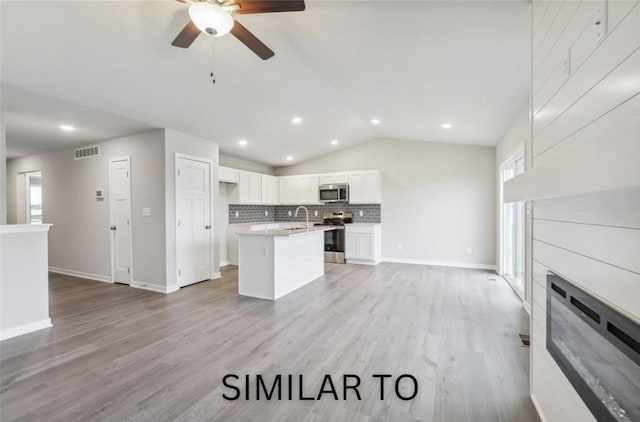 kitchen featuring visible vents, open floor plan, vaulted ceiling, appliances with stainless steel finishes, and a sink