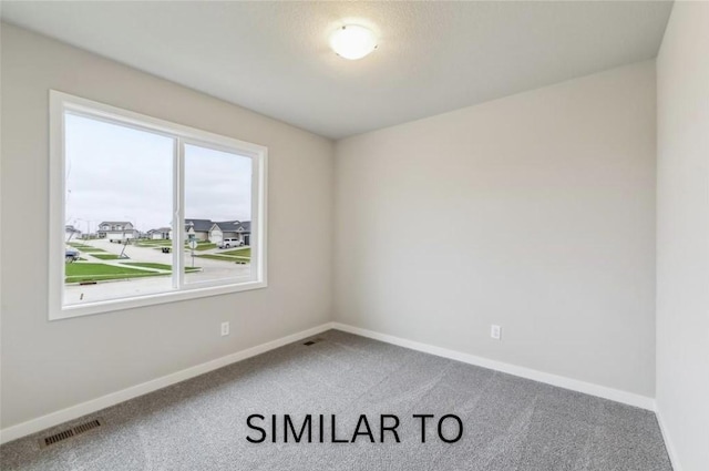 carpeted spare room featuring visible vents and baseboards