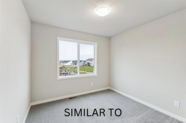 carpeted spare room with visible vents and baseboards