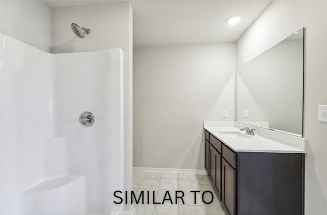 bathroom with baseboards, walk in shower, and vanity