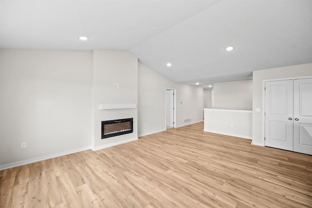 1811 Tuscany Dr SE, Altoona, IA 50009 - unfurnished living room with light wood-style flooring, vaulted ceiling, a glass covered fireplace, recessed lighting, and baseboards