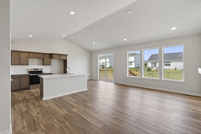 1811 Tuscany Dr SE, Altoona, IA 50009 - kitchen featuring stainless steel electric range, light wood finished floors, lofted ceiling, open floor plan, and a kitchen island with sink